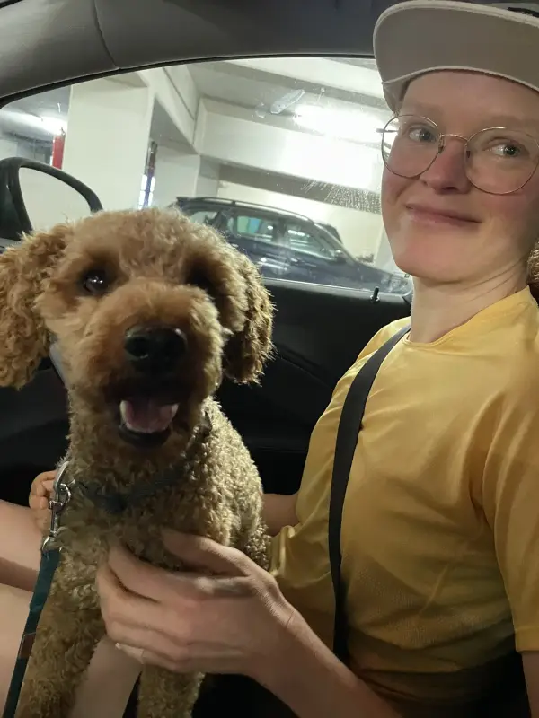 Rexi im Auto, im Arm meiner Freundin Helga in gelbem Shirt und Basecap